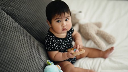 Téléchargez les photos : Adorable hispanic baby sitting on bed at bedroom - en image libre de droit