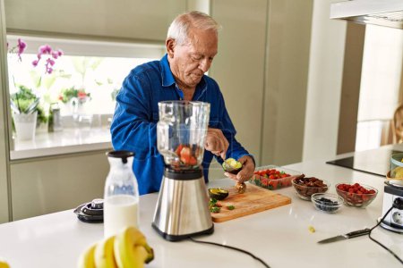 Foto de Hombre mayor cortando aguacate en la cocina - Imagen libre de derechos