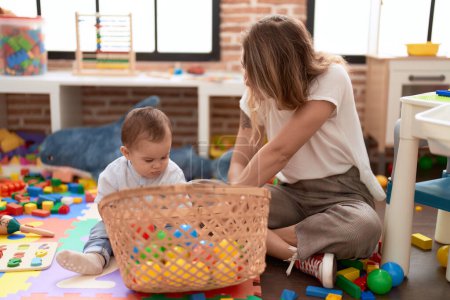 Photo for Mother and son playing with balls sitting on floor at kindergarten - Royalty Free Image