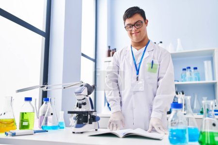 Téléchargez les photos : Homme trisomique portant l'uniforme scientifique debout au laboratoire - en image libre de droit