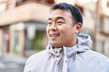 Téléchargez les photos : Young chinese man smiling confident standing at street - en image libre de droit