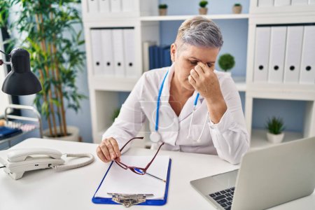 Photo for Middle age woman wearing doctor uniform stressed working at clinic - Royalty Free Image