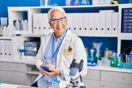 Téléchargez les photos : Senior man scientist using smartphone at laboratory - en image libre de droit