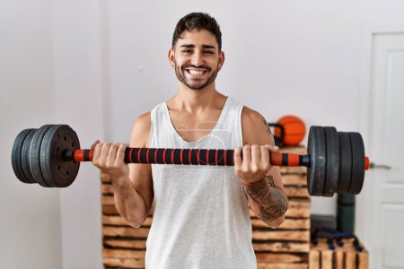 Photo for Young hispanic man training with weighs smiling with a happy and cool smile on face. showing teeth. - Royalty Free Image