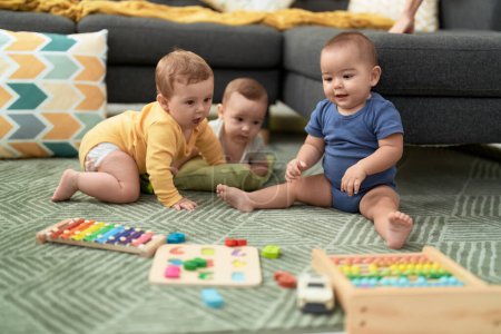 Foto de Grupo de niños pequeños jugando con juguetes sentados en el suelo en casa - Imagen libre de derechos