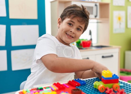 Téléchargez les photos : Adorable hispanic boy playing with construction blocks sitting on table at kindergarten - en image libre de droit