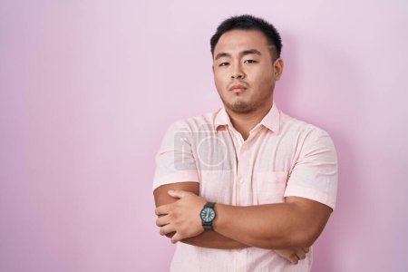 Photo for Chinese young man standing over pink background skeptic and nervous, disapproving expression on face with crossed arms. negative person. - Royalty Free Image