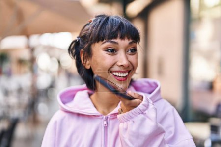 Téléchargez les photos : Jeune femme souriant confiant parler sur le smartphone à la rue - en image libre de droit