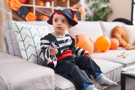 Téléchargez les photos : Adorable hispanic boy having halloween party holding pumpkin basket and car toy at home - en image libre de droit