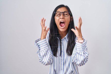 Photo for Young hispanic woman wearing glasses crazy and mad shouting and yelling with aggressive expression and arms raised. frustration concept. - Royalty Free Image