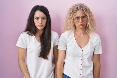 Photo for Mother and daughter standing together over pink background depressed and worry for distress, crying angry and afraid. sad expression. - Royalty Free Image