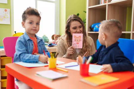 Foto de Profesor con niños sentados en la mesa teniendo clases de idioma en el jardín de infantes - Imagen libre de derechos