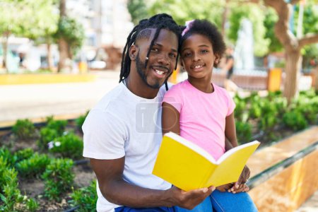 Téléchargez les photos : Père et fille lisant un livre assis ensemble sur un banc au parc - en image libre de droit