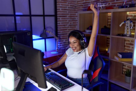 Téléchargez les photos : Jeune femme arabe streamer jouer jeu vidéo avec l'expression gagnante à la salle de jeu - en image libre de droit