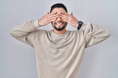 Photo for Young handsome man standing over isolated background covering eyes with hands smiling cheerful and funny. blind concept. - Royalty Free Image