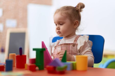 Téléchargez les photos : Adorable fille caucasienne jouer avec des blocs de construction debout à la maternelle - en image libre de droit
