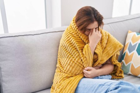 Téléchargez les photos : Jeune femme souffrant de maux de tête couvrant avec une couverture à la maison - en image libre de droit