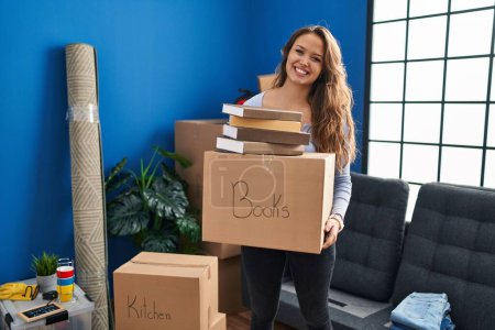 Photo for Young hispanic woman moving to a new home holding boxes smiling with a happy and cool smile on face. showing teeth. - Royalty Free Image