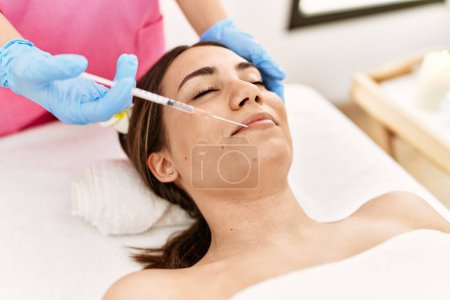 Photo for Young hispanic woman having anti-aging treatment at beauty center. - Royalty Free Image