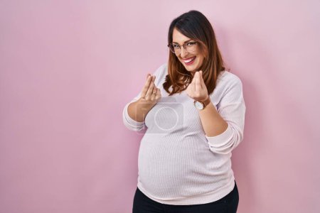 Photo for Pregnant woman standing over pink background doing money gesture with hands, asking for salary payment, millionaire business - Royalty Free Image