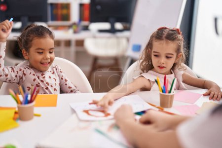 Photo for Two kids preschool students having lesson with teacher at classroom - Royalty Free Image