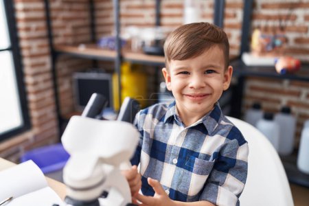 Foto de Adorable hispanic boy student smiling confident using microscope at laboratory classroom - Imagen libre de derechos