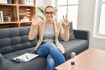 Photo for Young woman working at consultation office showing and pointing up with fingers number eight while smiling confident and happy. - Royalty Free Image