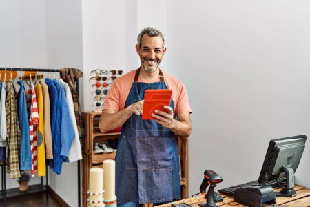 Photo for Middle age grey-haired man shop assistant using touchpad at clothing store - Royalty Free Image