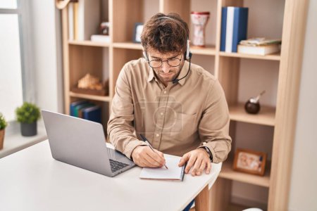 Foto de Young man call center agent writing on notebook working at office - Imagen libre de derechos