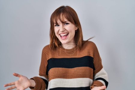 Téléchargez les photos : Young beautiful woman wearing striped sweater over isolated background smiling cheerful with open arms as friendly welcome, positive and confident greetings - en image libre de droit