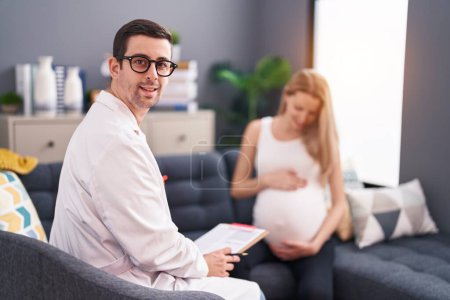 Téléchargez les photos : Homme et femme médecin et patiente enceinte ayant une consultation médicale à domicile - en image libre de droit