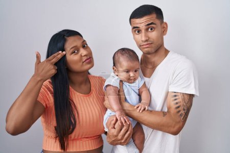 Photo for Young hispanic couple with baby standing together over isolated background shooting and killing oneself pointing hand and fingers to head like gun, suicide gesture. - Royalty Free Image