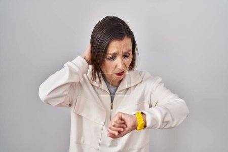 Photo for Middle age hispanic woman standing over isolated background looking at the watch time worried, afraid of getting late - Royalty Free Image