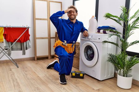 Téléchargez les photos : Young hispanic man working on washing machine stressed and frustrated with hand on head, surprised and angry face - en image libre de droit