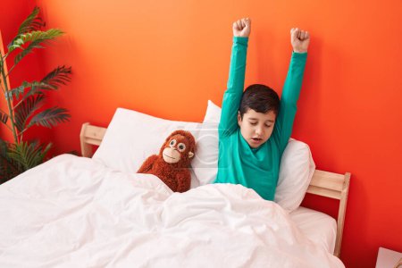 Téléchargez les photos : Adorable garçon hispanique se réveillant bras tendus dans la chambre - en image libre de droit