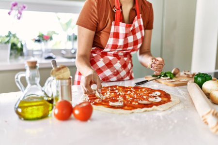 Photo for Young beautiful hispanic woman preparing italian pizza at the kitchen - Royalty Free Image