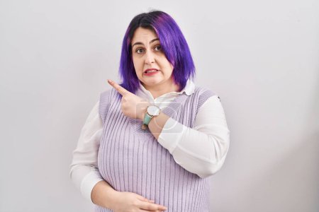 Photo for Plus size woman wit purple hair standing over white background pointing aside worried and nervous with forefinger, concerned and surprised expression - Royalty Free Image