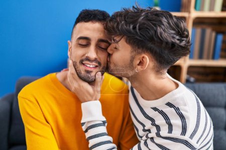 Téléchargez les photos : Deux couples d'hommes s'embrassant et s'embrassant assis sur le canapé à la maison - en image libre de droit