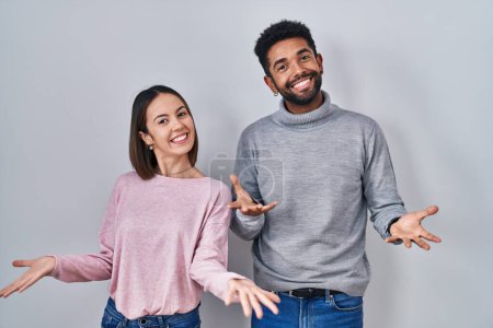 Photo for Young hispanic couple standing together smiling cheerful with open arms as friendly welcome, positive and confident greetings - Royalty Free Image