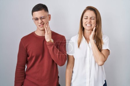 Téléchargez les photos : Mother and son standing together over isolated background touching mouth with hand with painful expression because of toothache or dental illness on teeth. dentist - en image libre de droit
