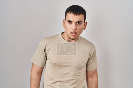 Foto de Hombre árabe joven con camiseta casual en la cara de choque, con aspecto escéptico y sarcástico, sorprendido con la boca abierta - Imagen libre de derechos
