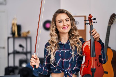 Téléchargez les photos : Young woman artist holding violin at music studio - en image libre de droit