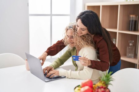 Photo for Two women mother and daughter using laptop and credit card at home - Royalty Free Image
