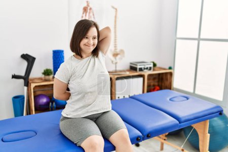 Foto de Brunette woman with down syndrome stretching arms at physiotherapy clinic - Imagen libre de derechos