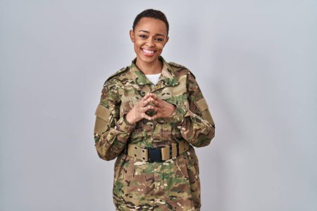 Foto de Beautiful african american woman wearing camouflage army uniform hands together and fingers crossed smiling relaxed and cheerful. success and optimistic - Imagen libre de derechos