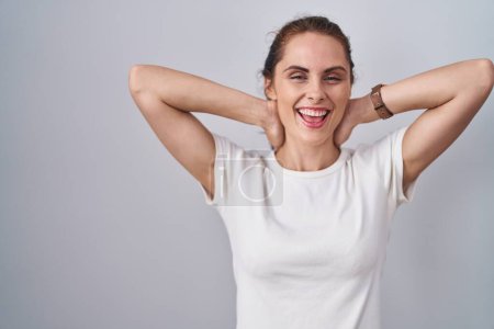 Téléchargez les photos : Beautiful brunette woman standing over isolated background relaxing and stretching, arms and hands behind head and neck smiling happy - en image libre de droit
