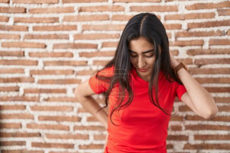 Téléchargez les photos : Young teenager girl standing over bricks wall suffering of backache, touching back with hand, muscular pain - en image libre de droit