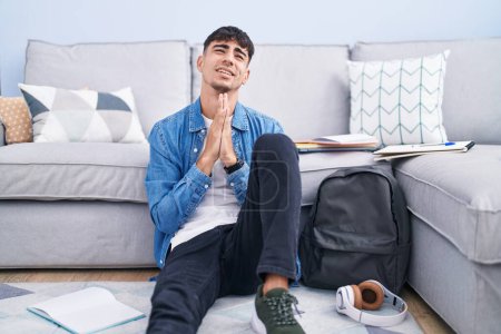 Photo for Young hispanic man sitting on the floor studying for university begging and praying with hands together with hope expression on face very emotional and worried. begging. - Royalty Free Image
