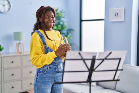 Téléchargez les photos : African american woman musician smiling confident holding trumpet at home - en image libre de droit