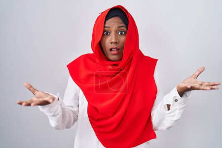 Téléchargez les photos : Young arab woman wearing traditional islamic hijab scarf clueless and confused with open arms, no idea concept. - en image libre de droit